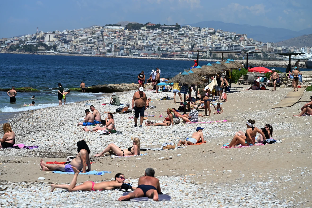 Παραλία γεμάτη κόσμο, με λουόμενους να αναζητούν σκιά κάτω από ομπρέλες και ψάθινα στέγαστρα λόγω της έντονης ζέστης. Πηγή: Sportime
