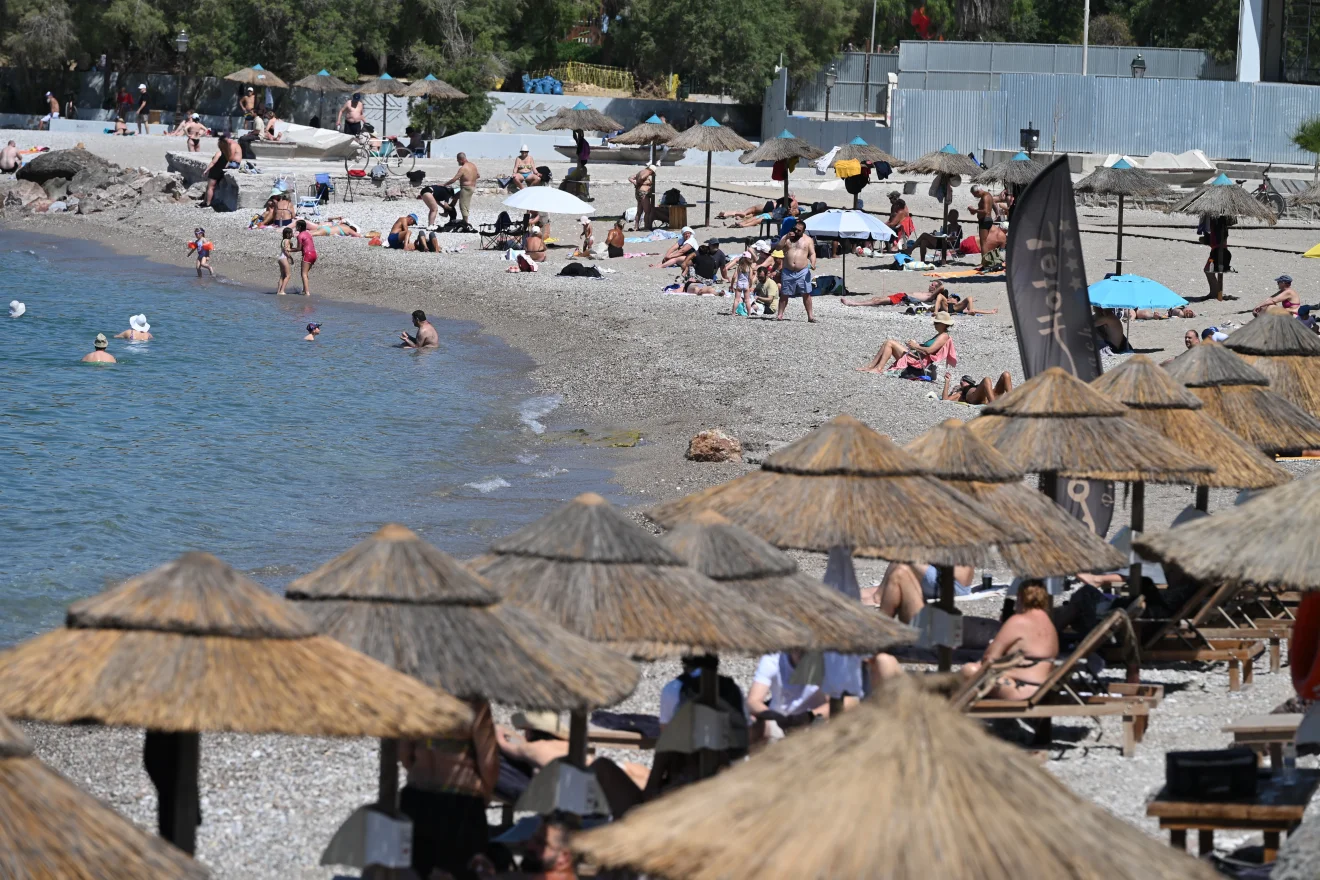 Λουόμενοι απολαμβάνουν τη θάλασσα και τον ήλιο σε οργανωμένη παραλία, αναζητώντας δροσιά μέσα στις υψηλές θερμοκρασίες του καλοκαιριού. Πηγή: ΙΝΤΙΜΕ