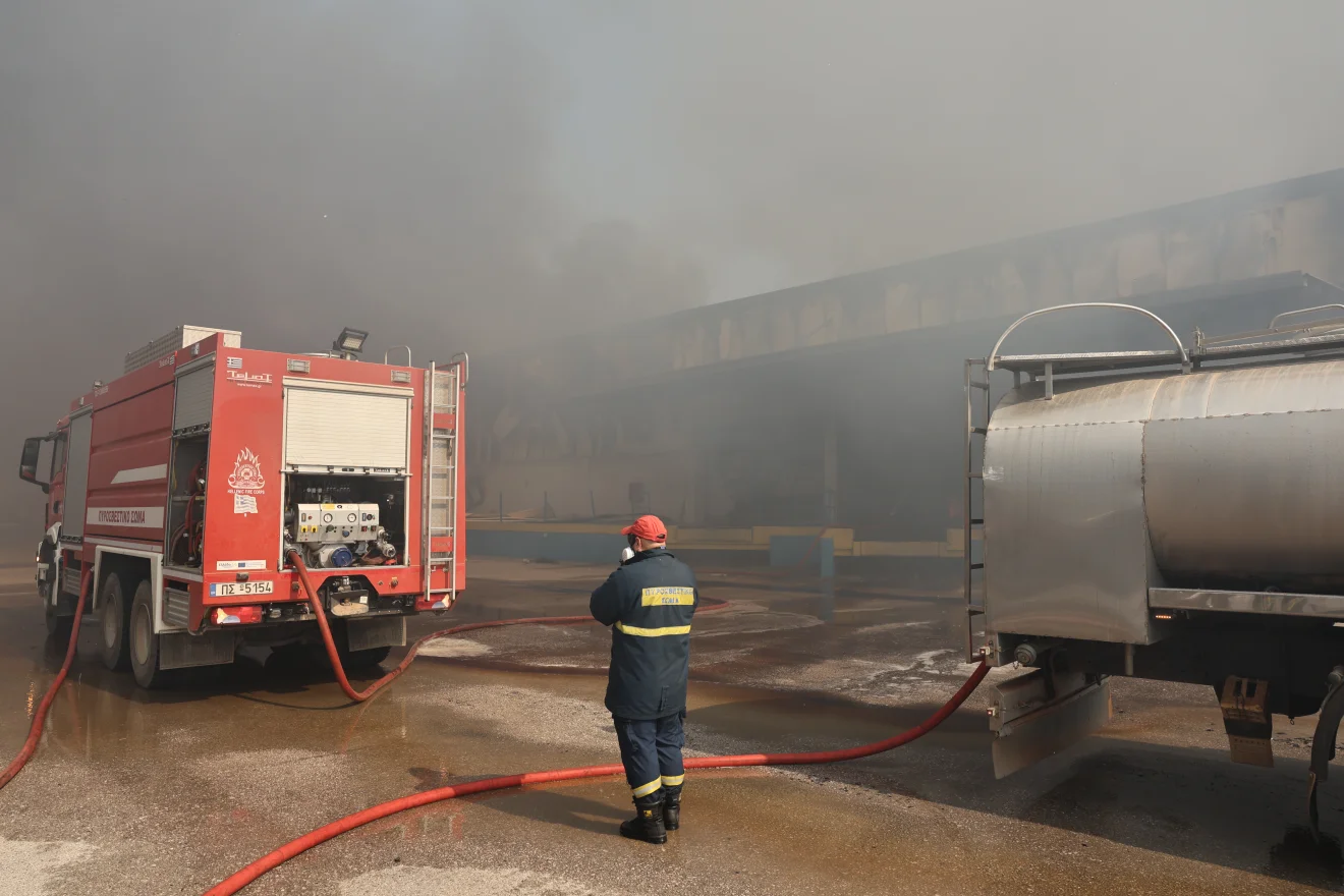Πυροσβεστικό όχημα και υδροφόρα επιχειρούν σε χώρο με έντονο καπνό, μετά από φωτιά σε βιομηχανικές εγκαταστάσεις. Πηγή: ΙΝΤΙΜΕ.