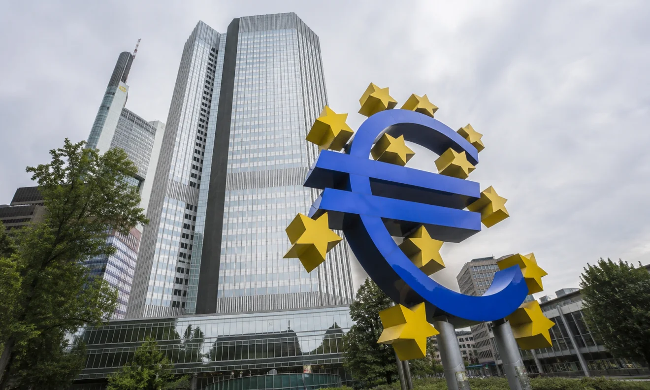 Το σύμβολο του ευρώ μπροστά από σύγχρονα κτίρια της Ευρωπαϊκής Κεντρικής Τράπεζας, σε εικόνα που παραπέμπει στην οικονομία της Ευρωζώνης. Πηγή: sportime.gr.