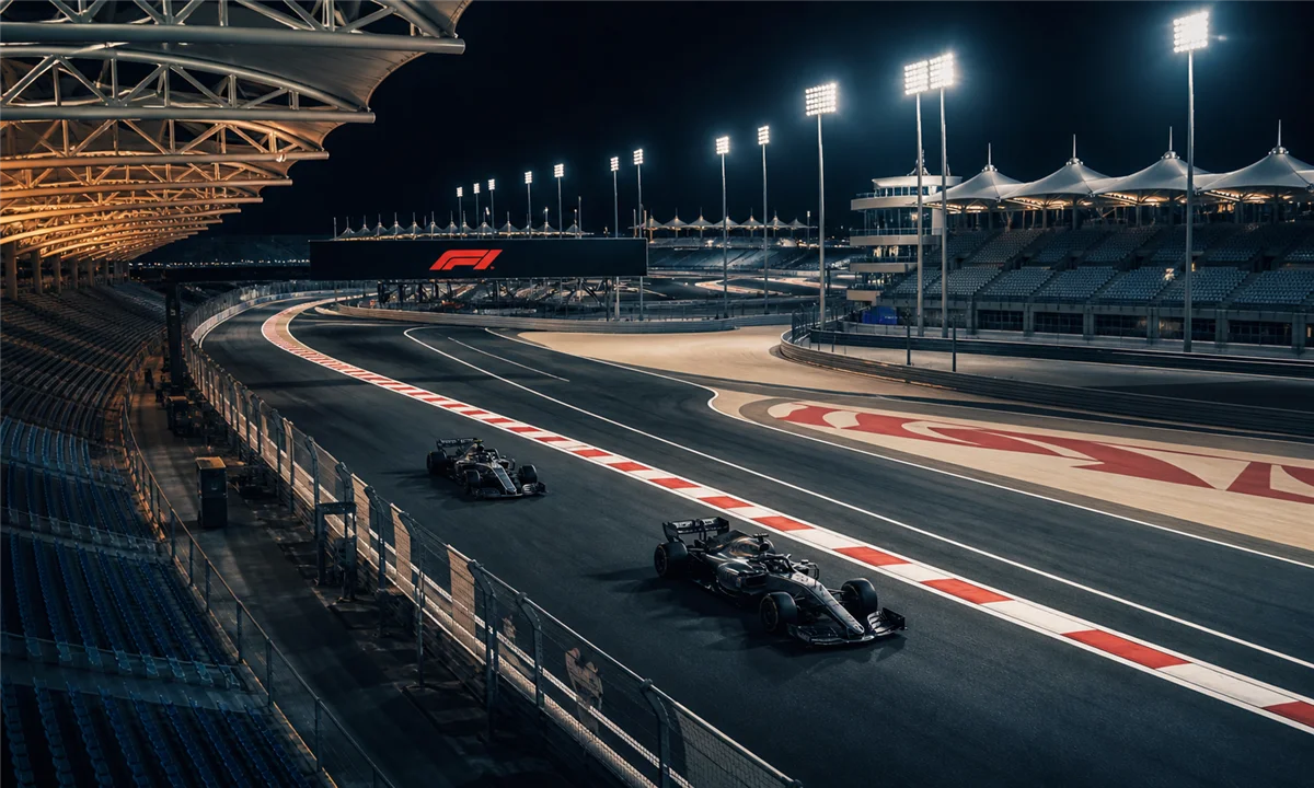Νυχτερινή πίστα Formula 1 με δύο αγωνιστικά αυτοκίνητα σε σκηνικό που παραπέμπει σε αγώνα sprint — Πηγή: Sportime.gr