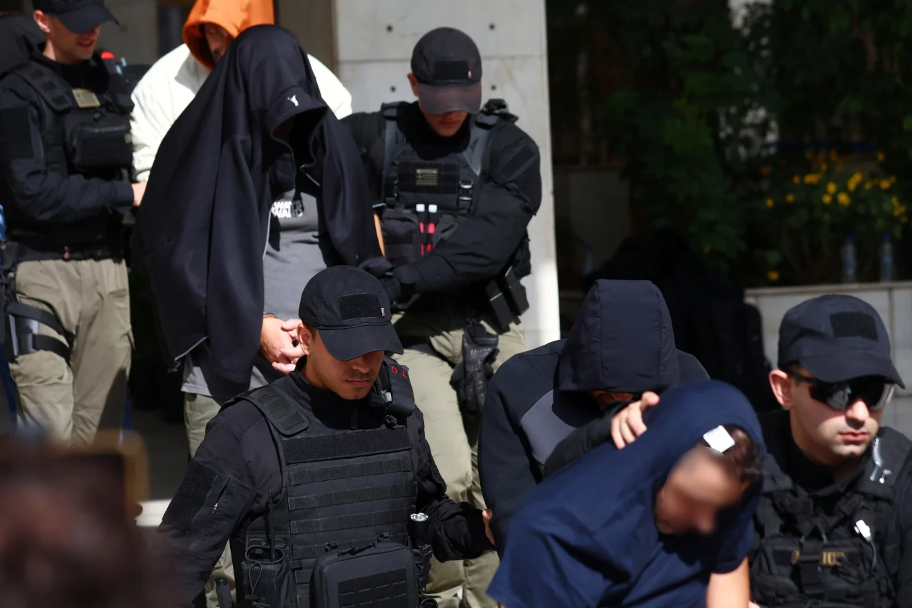 Μεταγωγή προσώπων με καλυμμένα χαρακτηριστικά και τη συνοδεία αστυνομικών, έξω από κτίριο των δικαστικών Αρχών. Πηγή: INTIME.