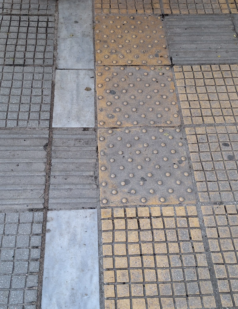 Συνδυασμός πλακιδίων όδευσης και προειδοποίησης σε αστικό πεζοδρόμιο